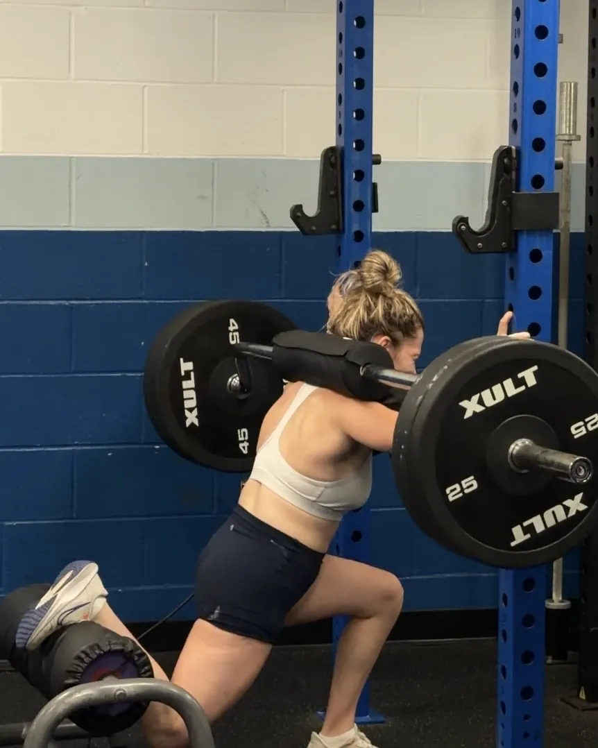 Athlete in a rear-foot-elevated split squat under a loaded barbell